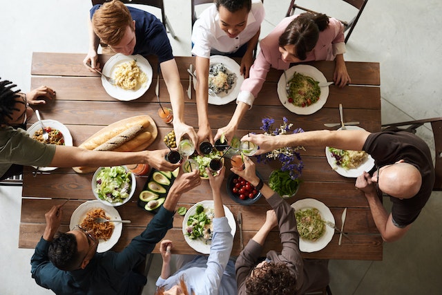 Das Bild zeigt ein leckeres Essen mit acht Freunden an einem Tisch.